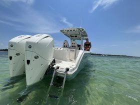 A woman relaxes on the deck of a boat in clear waters under a sunny sky, showcasing a perfect day for boating adventures.