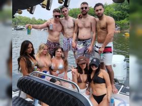 A lively group of friends enjoys a fun day on the water, posing on their boat with drinks in hand — perfect for summer parties and celebrations.