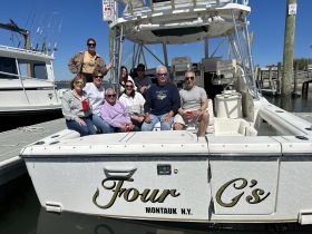 A cheerful group gathers on the deck of the 'Four G's' boat in Montauk, enjoying a sunny day together — perfect for celebrations and outings on the water.