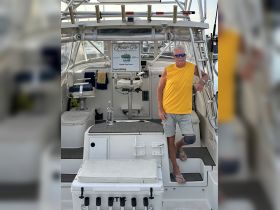 A captain stands at the helm of a fishing charter boat, showcasing the interior setup with seating and equipment — perfect for sportfishing adventures.