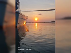 A serene sunset view featuring a boat silhouetted against the vibrant sky, perfect for capturing the tranquility of evening on the water.