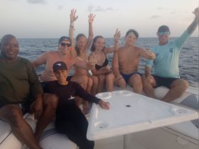 A cheerful group of friends and family enjoy their time on a boat, celebrating together against the backdrop of the ocean — perfect for memorable outings and adventures.