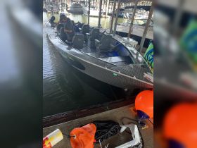 A man prepares a sleek fishing boat inside a covered dock, showcasing its modern seating and helm — perfect for a day on the water.