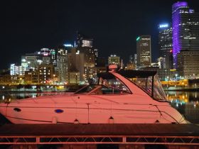 A sleek yacht docked at night with a vibrant city skyline in the background, showcasing the perfect blend of urban and nautical charm.