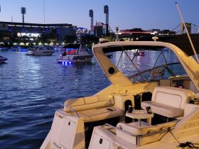 A beautifully lit boat docked at night with PNC Park in the background, showcasing a serene waterfront scene perfect for evening outings.