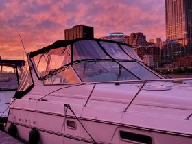 A stunning view of a yacht docked at sunset, showcasing its sleek design against a vibrant sky and city skyline.