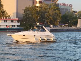 A sleek speedboat navigates the waters near the Carnegie Science Center, showcasing a perfect day for boating in the city.