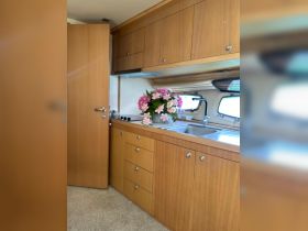 Interior view of a boat's kitchen area featuring wooden cabinetry and a floral arrangement, showcasing the cozy and functional design of the cabin space.