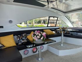 A stylish interior view of a boat's lounge area featuring comfortable seating and decorative elements, perfect for relaxing while on the water.