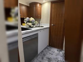 A well-appointed boat kitchen featuring elegant cabinetry and a floral centerpiece, perfect for preparing meals while on the water.