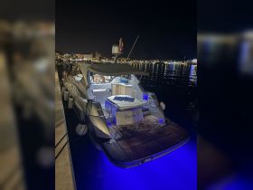 A beautifully lit yacht named 'Maria V' docked at night, showcasing its elegant design against a vibrant waterfront backdrop.