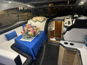 A beautifully arranged interior of a boat featuring a cozy seating area with a floral centerpiece, perfect for relaxing and enjoying the views while on the water.