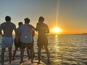 A group of friends enjoys a stunning sunset aboard a boat, capturing a perfect moment of camaraderie and celebration on the water.