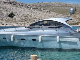 A sleek yacht docked in clear waters, showcasing its elegant design against a rocky backdrop — perfect for luxury boating experiences.