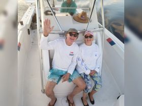 A cheerful couple waves from the helm of their boat, enjoying a sunny day on the water — perfect for memorable boating adventures.