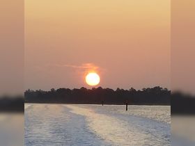 A serene sunset view over calm waters, showcasing the beauty of nature as the sun dips below the horizon — perfect for tranquil evening boat rides.