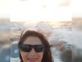 A joyful selfie taken while cruising on the ocean at sunset, capturing the thrill of boating adventures.