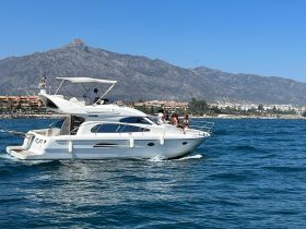 A lively group enjoys a day on a yacht cruising through beautiful waters, with stunning mountain views in the background — perfect for memorable outings.