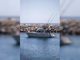 A fishing boat navigates the calm waters, showcasing a perfect day for fishing adventures. Ideal for those looking to enjoy a day on the sea.