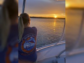 A serene sunset view from a boat, with a guest enjoying the tranquil waters — perfect for sunset cruises and relaxation on the water.