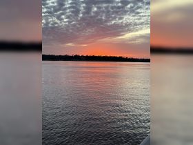A stunning sunset casts vibrant colors over the water, creating a picturesque scene perfect for evening boat trips or relaxation by the shore.
