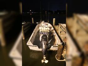 A fishing boat docked at night, showcasing its sleek design and fishing gear, perfect for nighttime adventures on the water.