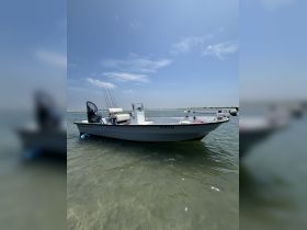 A fishing boat anchored in shallow waters under a clear blue sky, showcasing its sleek design and fishing gear — perfect for a day on the water.