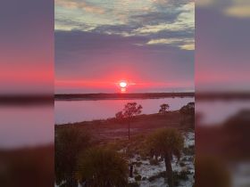 A stunning sunset casts vibrant colors over the coastline, creating a picturesque scene perfect for romantic evenings or tranquil moments by the water.