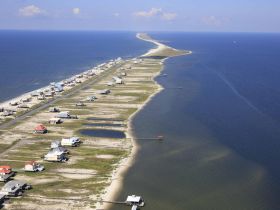 A stunning aerial view of a coastal landscape showcasing a long stretch of land bordered by the ocean, perfect for exploring the natural beauty of the area.