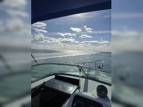 A stunning view from the helm of a boat, showcasing the sparkling water and a distant lighthouse under a bright sky — perfect for showcasing the beauty of a day on the water.