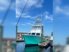 A striking fishing boat docked at the marina, showcasing its sleek design and vibrant colors against a clear blue sky.