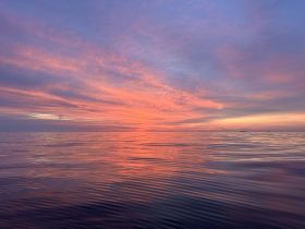 A breathtaking sunset over calm ocean waters, showcasing vibrant colors and serene reflections — a perfect moment for relaxation and appreciation of nature's beauty.