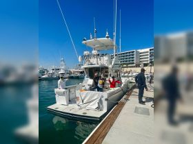 Crew members wave from the deck of a boat at the marina, showcasing a welcoming atmosphere for guests ready to embark on their adventure.