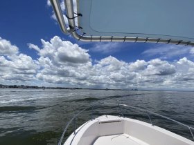 A scenic view from the bow of a boat, showcasing the vast waterway and dramatic cloud formations — perfect for a day out on the water.