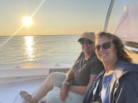 Two friends enjoy a beautiful sunset on a boat, capturing a moment of relaxation and camaraderie on the water.