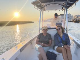 A group of friends relaxes on a boat during a picturesque sunset cruise, enjoying the serene waters and beautiful scenery.