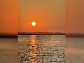 A stunning sunset casts a golden reflection on the water, creating a picturesque scene perfect for evening boat trips or romantic getaways.