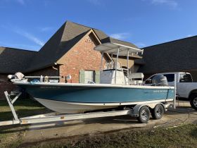 A side view of a Sea Hunt boat parked in front of a house, showcasing its sleek design and readiness for the water.
