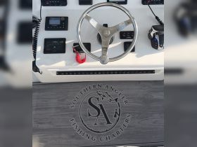 A close-up view of the helm and console of a fishing charter boat, showcasing the controls and equipment essential for navigation and fishing adventures.