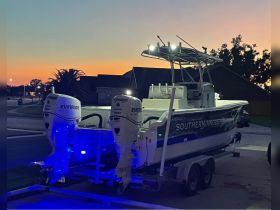 A sleek fishing boat named 'Southern Angler' is docked on its trailer, illuminated by blue lights against a stunning sunset backdrop, perfect for evening fishing trips.