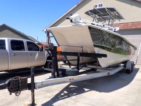 A sleek boat is showcased on its trailer in a driveway, highlighting its design and readiness for adventure.