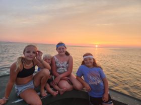 A group of children enjoys a beautiful sunset on a boat, capturing a memorable family moment on the water.