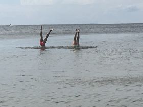 Two individuals enjoy a playful moment in the water, showcasing fun swimming activities — perfect for summer adventures and beach outings.