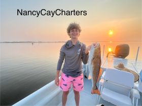 A young boy proudly displays his catch while fishing on a boat at sunset, capturing the thrill of a successful day on the water.