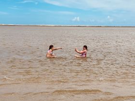 Two girls enjoy a playful moment while swimming in shallow water, capturing the essence of summer fun and beach adventures.