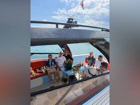 A lively group enjoys a boat party with cocktails and snacks, creating a festive atmosphere on the water — perfect for celebrations and gatherings.
