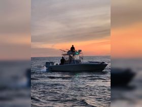 A fishing boat navigates the ocean at sunset, creating a picturesque scene perfect for evening excursions and fishing adventures.