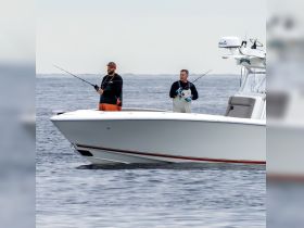 Two anglers enjoy a fishing trip on a boat, casting their lines into the open ocean — a perfect day for fishing enthusiasts.