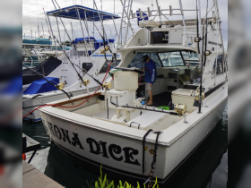 A view of the interior of the fishing boat 'Kona Dice,' showcasing the helm and seating area, perfect for fishing trips and adventures on the water.