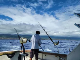 A fisherman prepares to cast his line from a boat, enjoying a day of fishing on the open water, surrounded by stunning coastal scenery.